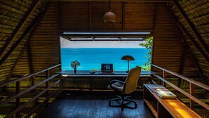 A room with a view of the ocean, a desk with a chair, a lamp, and a bench. - Finca Exotica ecolodge (Puerto Jiménez)