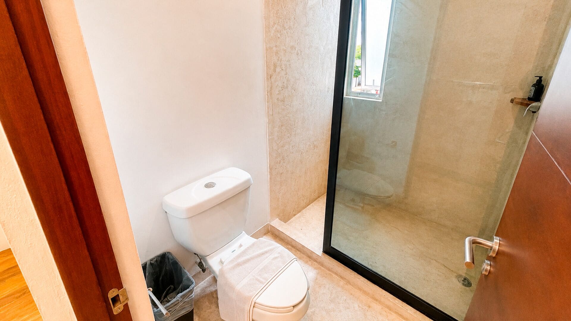 Een badkamer met toilet, douche en een glazen deur.