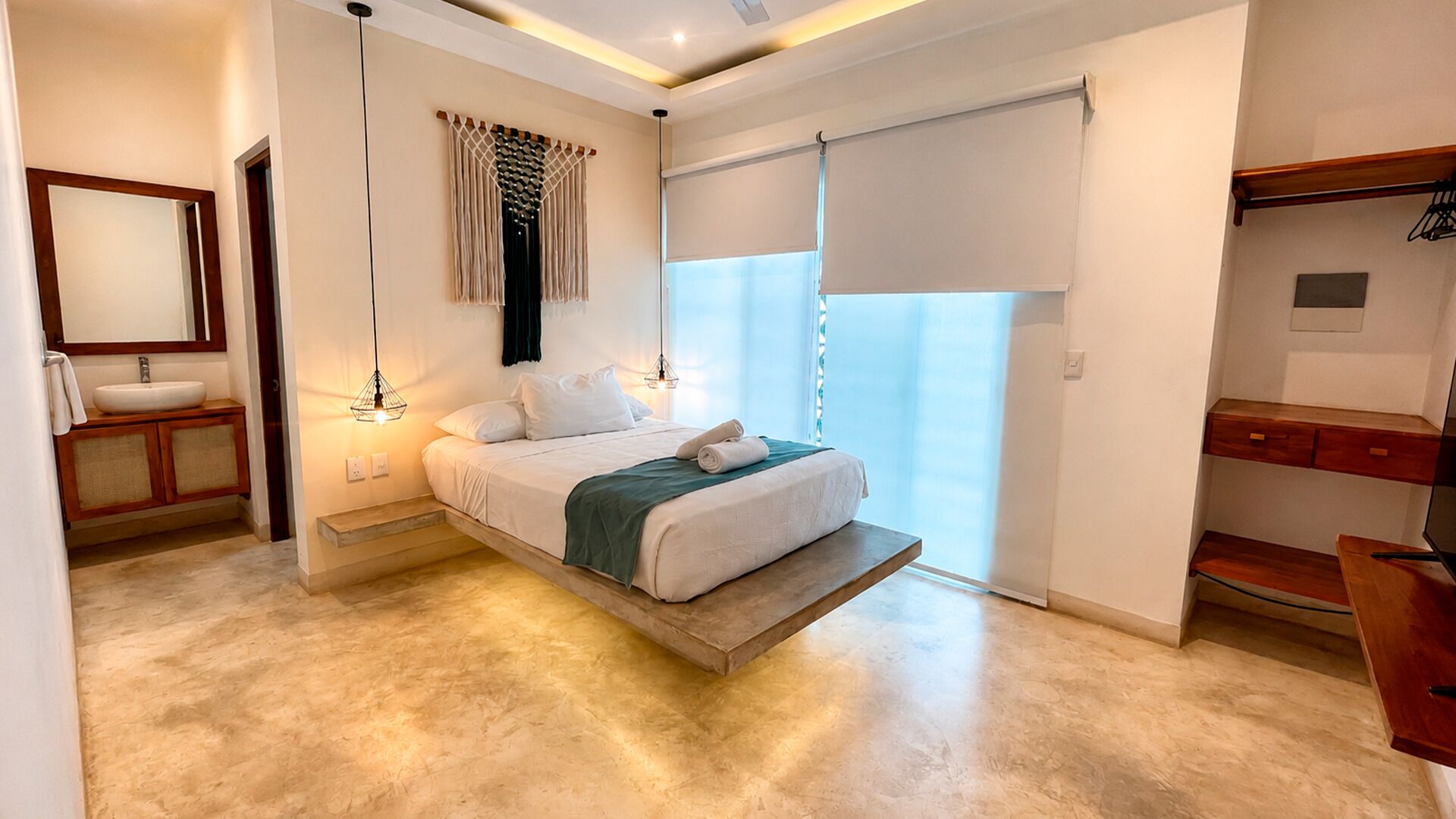 Een slaapkamer met een bed, nachtkastje, hanglamp en uitzicht.