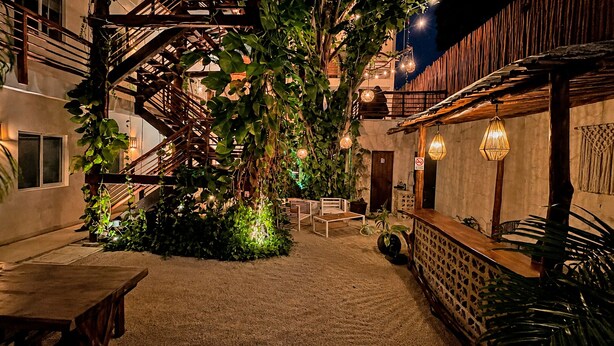 Une cour intérieure dotée d’un escalier en bois, d’un espace salon et de luminaires suspendus.