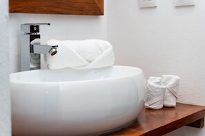 Ein Badezimmer mit einem weißen Waschbecken, einem Chromarmaturen und einem Holzboden mit zwei weißen Handtüchern.