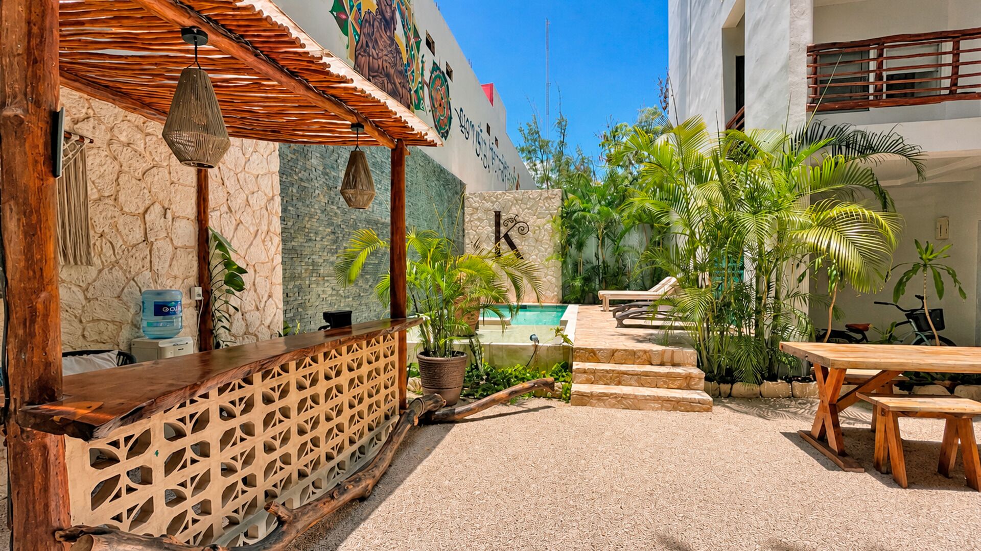 A poolside area with a wooden bar, lounge chairs, and potted plants.