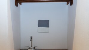 A compact kitchen with a wooden countertop, a single sink, and two cabinets with fabric doors. - Kanté Hotel - Downtown Tulum (Tulum)