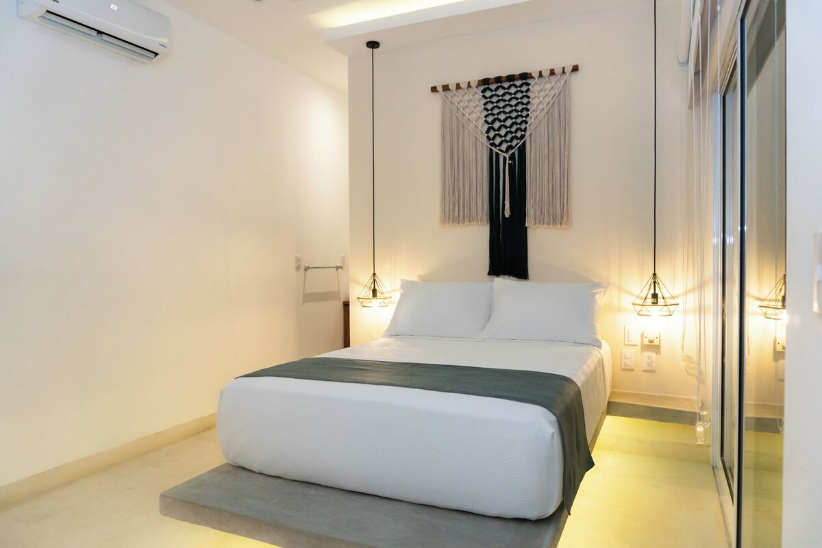 Une chambre moderne avec un lit, des lampes de chevet et un climatiseur fixé au mur.