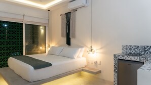 A modern bedroom with a bed, bedside table, air conditioning unit, and a patterned refrigerator. - Kanté Hotel - Downtown Tulum (Tulum)