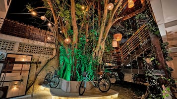 Un atrio interior con escalera, bicicletas y un árbol con luces colgantes.