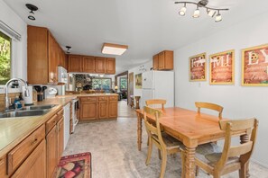 A kitchen with wooden cabinets, a dining table with chairs, and a refrigerator.