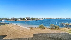 Una propiedad frente al agua con muelle, zona verde y cielo azul despejado.