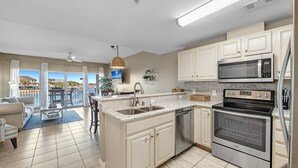 Una cocina moderna con una isla grande, electrodomésticos de acero inoxidable y vistas al exterior.