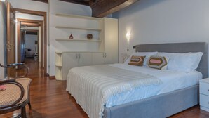 Un dormitorio con cama, mesitas de noche, un armario y una silla.