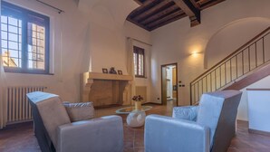 Amplia sala de estar con chimenea, una escalera y vistas al exterior.