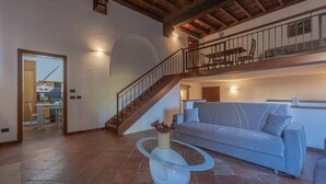 Un amplio salón con una escalera, un sofá y una mesa de centro de vidrio.