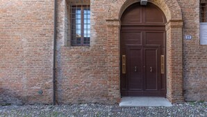 Un edificio de ladrillo con una gran entrada en arco, una ventana pequeña y una puerta con pomo de latón.