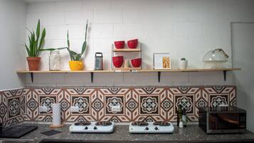 A kitchen with a backsplash of patterned tiles, a stove, a microwave, and shelves with various kitchen items.