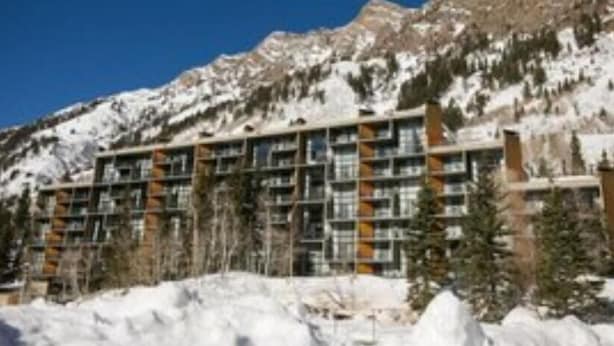 A multi-story hotel with a modern architectural design, surrounded by snow-covered mountains and trees. - Iron Blosam Lodge at Snowbird with all the amenities you want. (Sandy)