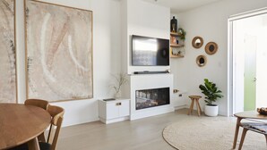 Un salon moderne avec une cheminée, un téléviseur et un coin repas.