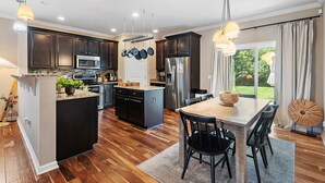 A modern kitchen with dark cabinets, stainless steel appliances, and a central island with seating. - Elegant Home with Large Yard (Nashville)