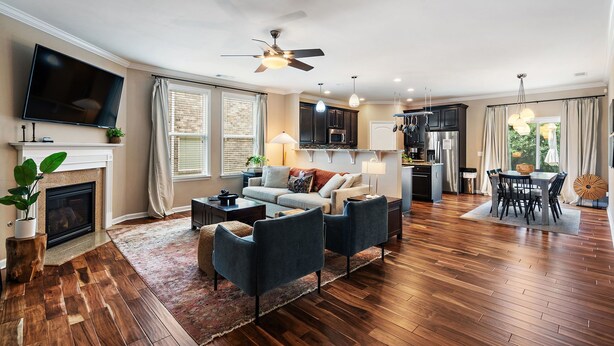 A spacious living room with a fireplace, a television, and a dining area with a table and chairs. - Elegant Home with Large Yard (Nashville)