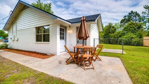 A single-story house with a patio, a table with chairs, and a brown umbrella. - Stylish Family Friendly Bungalow, Tvs, Royal Beds (Hinesville)