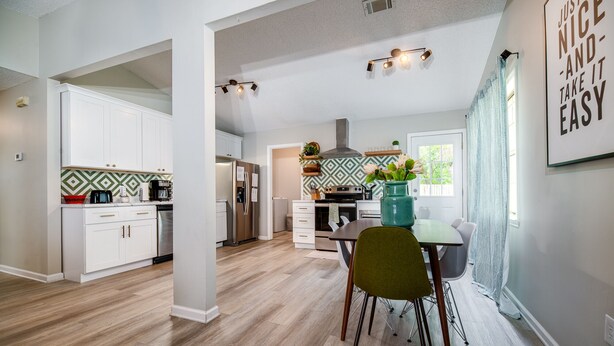 A spacious kitchen with modern appliances, a dining area with a table and chairs, and a view of the outdoors. - Stylish Family Friendly Bungalow, Tvs, Royal Beds (Hinesville)