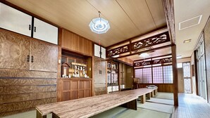 Una habitación japonesa tradicional con suelo de tatami, una mesa baja de madera, puertas correderas y un ventilador de techo.