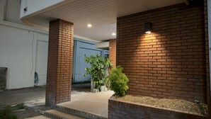 Una entrada moderna de edificio con paredes de ladrillo, un camino empedrado y una planta en maceta.