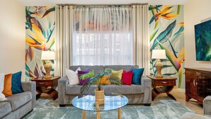 A living room with a sofa, two armchairs, a glass coffee table, and a side table with a lamp.