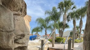 A set of stone steps leading up to a building, surrounded by palm trees and a clear sky.