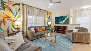 A living room with a sofa, armchairs, a coffee table, and a TV.