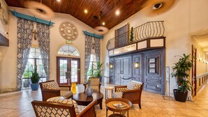 A lobby with patterned chairs, a coffee table, and potted plants.