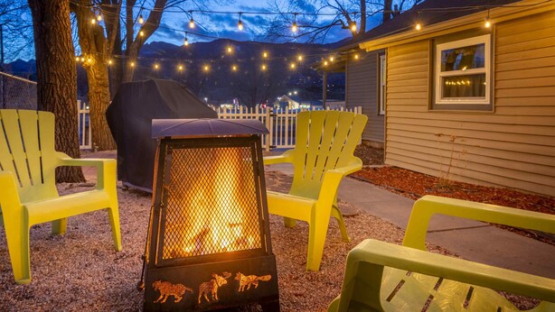 A patio area with a fire pit, yellow chairs, and string lights. - Clean and comfortable with astounding views of Pikes Peak.  (Colorado Springs)
