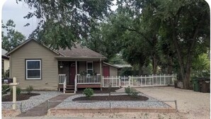 A single-story house with a front porch, a white picket fence, and a gravel driveway. - Clean and comfortable with astounding views of Pikes Peak.  (Colorado Springs)