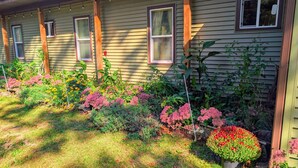 Ein Haus mit Garten und einer Veranda mit Holzbalken und mehreren Fenstern.