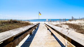 A wooden boardwalk leading to a beach with a flag in the distance. - Beachfront 1BR + Bunk Alcove @ Phoenix East • Sleeps 6 • Amazing Views & Resort Amenities (Orange Beach)