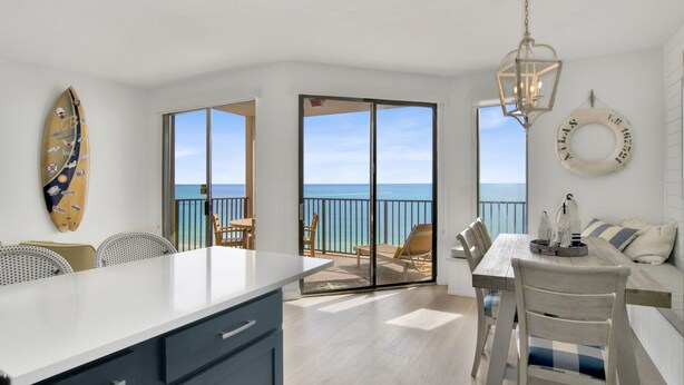 A modern kitchen with a large island, a dining area with a view of the sea, and a balcony with a glass door. - Beachfront 1BR + Bunk Alcove @ Phoenix East • Sleeps 6 • Amazing Views & Resort Amenities (Orange Beach)