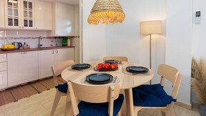 A modern kitchen with white cabinets, a round dining table with blue plates, and a hanging light fixture. - Beautiful apartment for 4 people with WIFI, pool, A/C, TV and terrace (Salou)