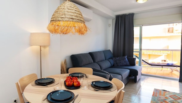 A dining area with a round table, chairs, and a hanging light fixture. - Beautiful apartment for 4 people with WIFI, pool, A/C, TV and terrace (Salou)