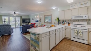 Una cocina moderna con armarios blancos, una isla grande y un cartel que dice 'BEACH HOUSE'.