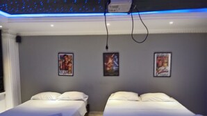 Ein Hotelzimmer mit zwei Betten, einer Deckenleuchte und drei Bildern an der Wand.