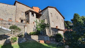 A stone building with a balcony, a white umbrella, and potted plants. - Beautiful  villa with WIFI, private pool, TV, terrace and panoramic view, close to Lucca (Chiatri)