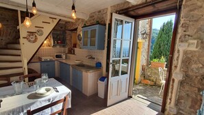 A rustic kitchen with a dining area, stone walls, and a view of the outdoors. - Beautiful  villa with WIFI, private pool, TV, terrace and panoramic view, close to Lucca (Chiatri)