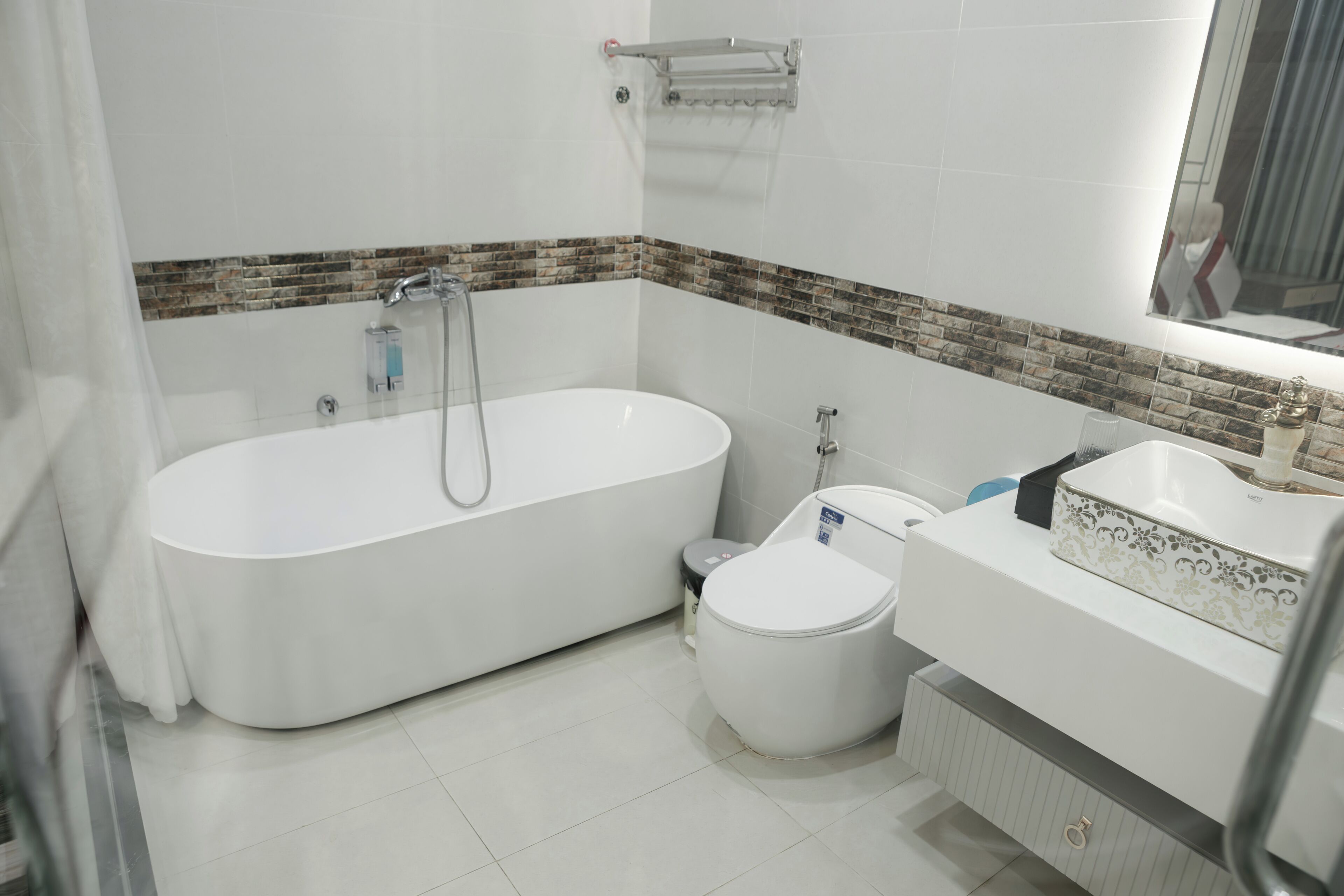 A modern bathroom with a freestanding bathtub, a toilet, and a vanity with a mirror.