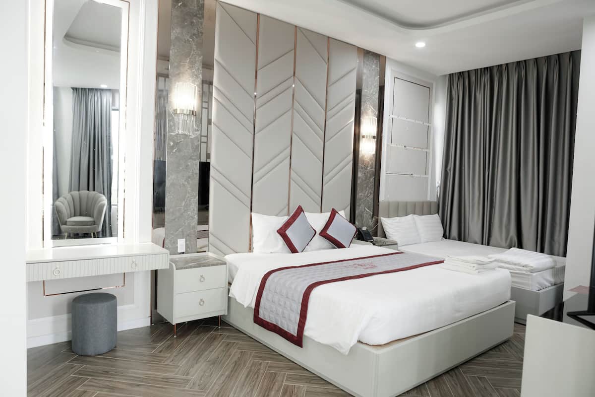 Une chambre d’hôtel moderne équipée d’un grand lit, d’une coiffeuse avec miroir, d’un bureau et d’une chaise.