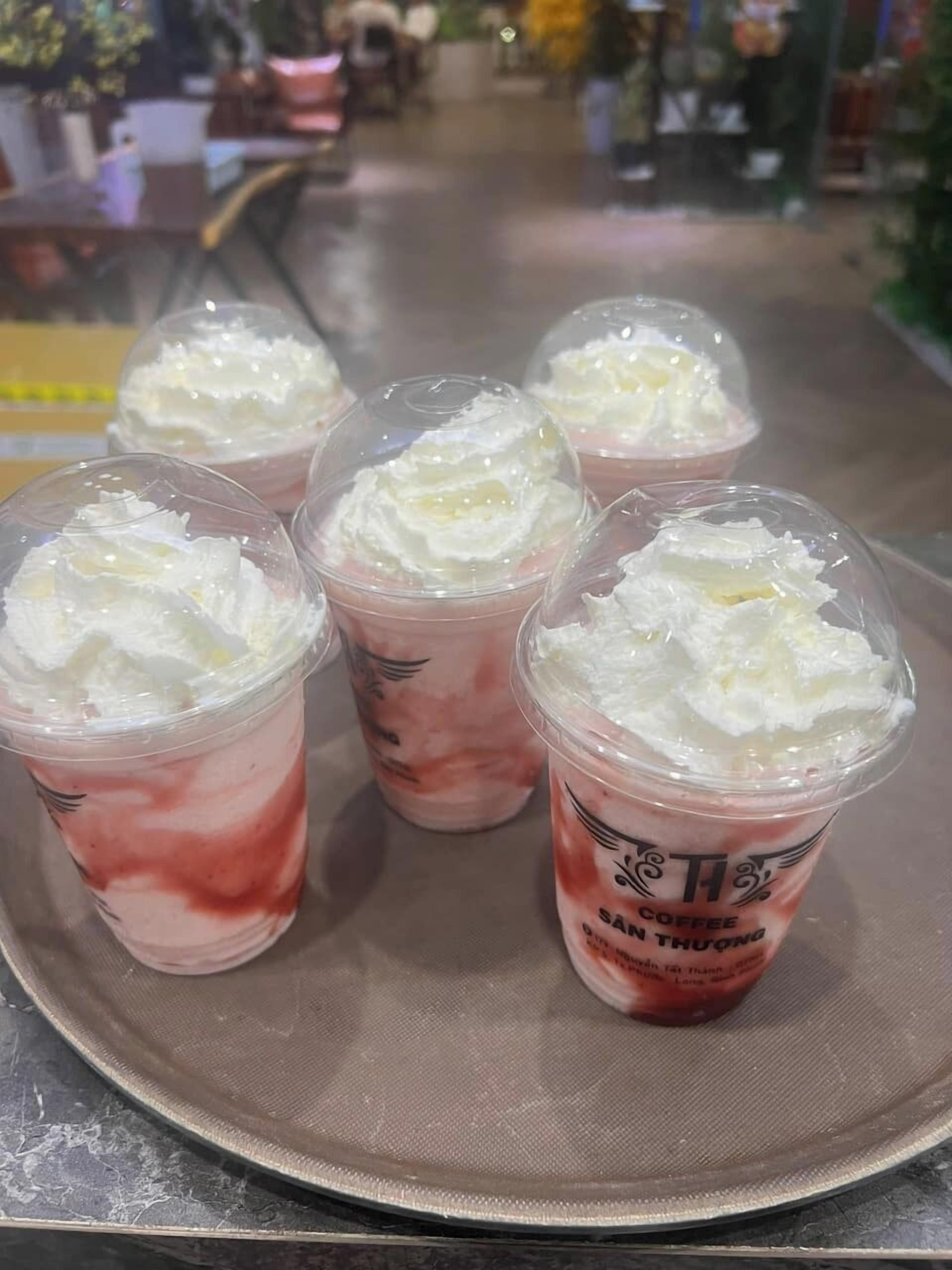 Five cups of iced coffee with whipped cream on a metal tray.