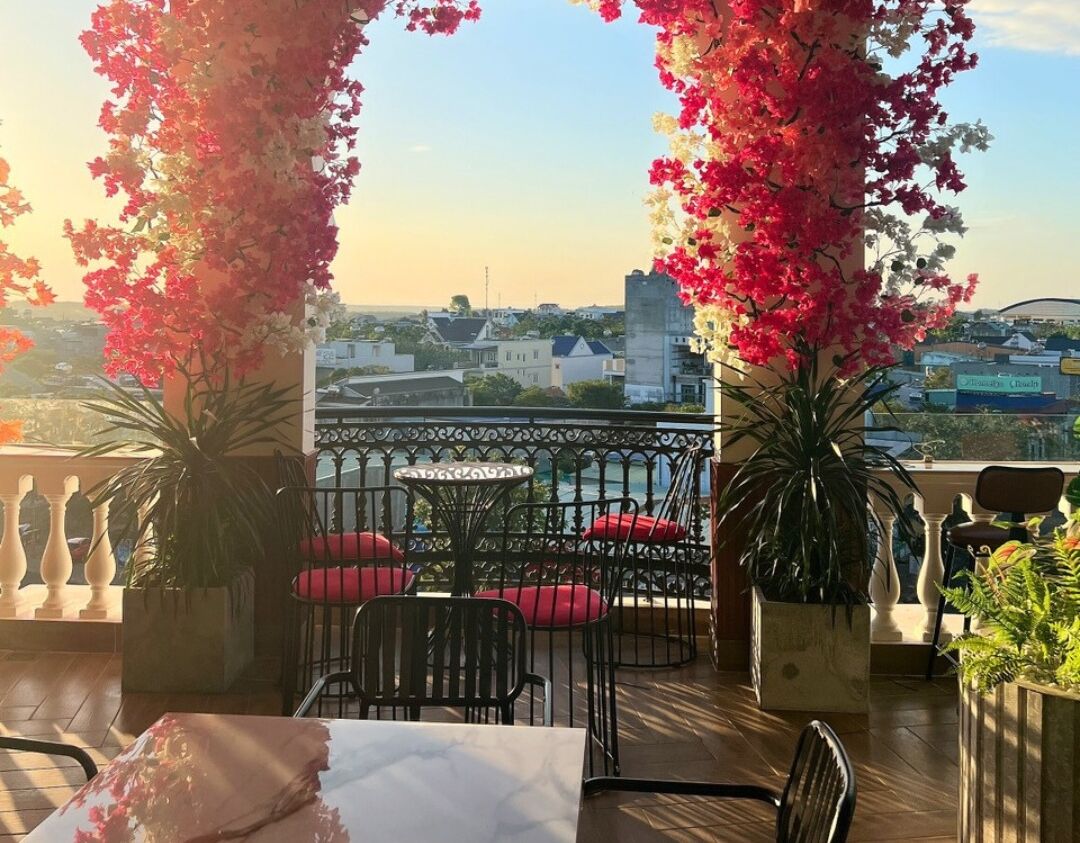 A terrace with a table and chairs, surrounded by potted plants and a railing.