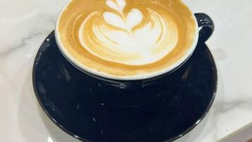 Una taza de café con arte de latte sobre un platillo negro.