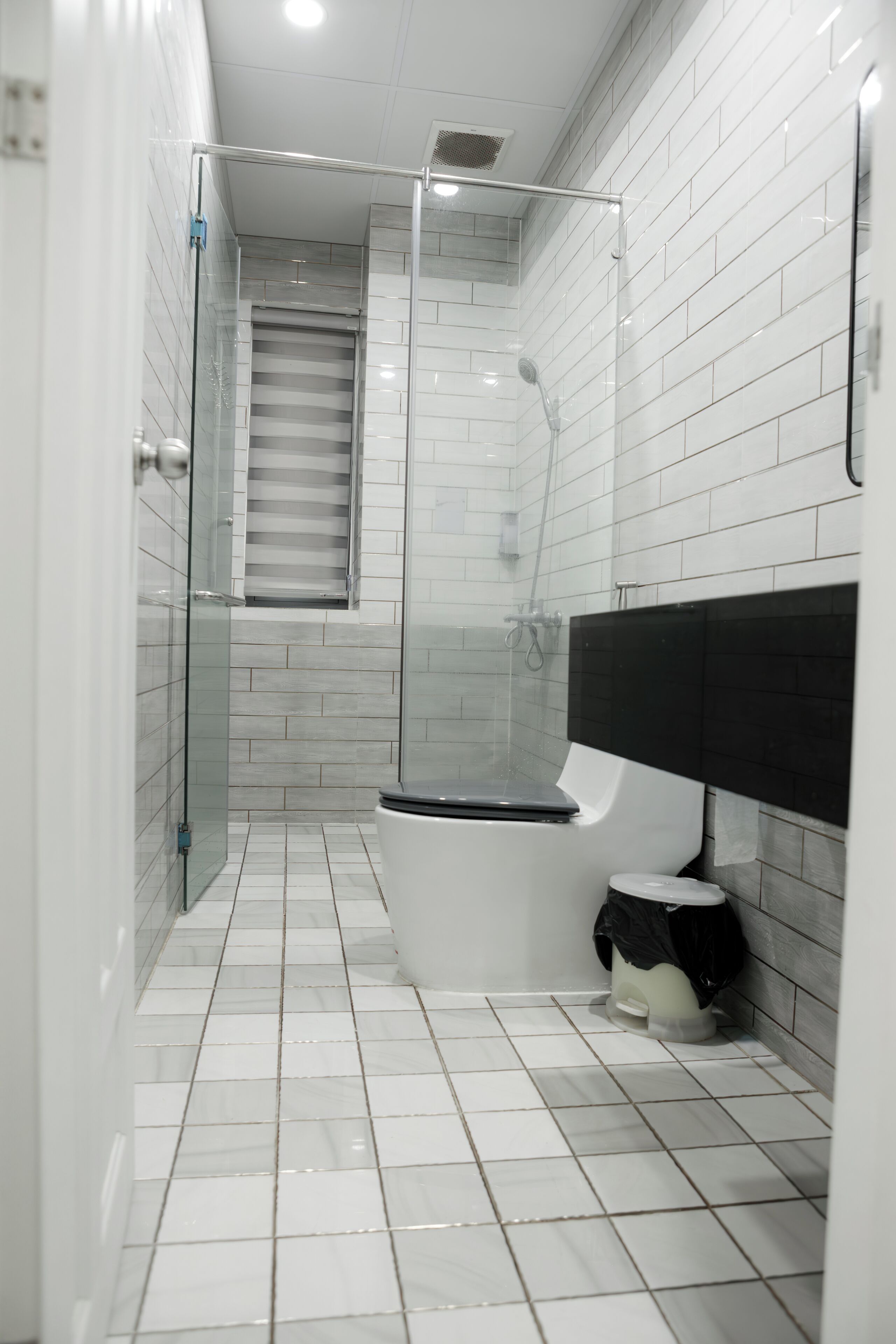A bathroom with a glass-enclosed shower, a toilet, and a sink with a black countertop.