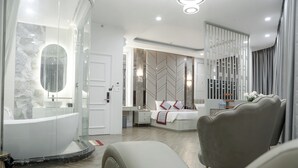 Un dormitorio moderno con una cama grande, una zona de estar y una ducha con paredes de cristal.