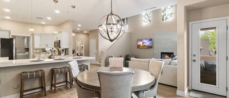A modern kitchen with a dining area, a living room with a fireplace, and a TV.