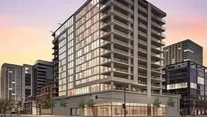 Un immeuble à plusieurs étages doté d’une architecture moderne, caractérisé par une structure d’angle remarquable et une série de balcons.